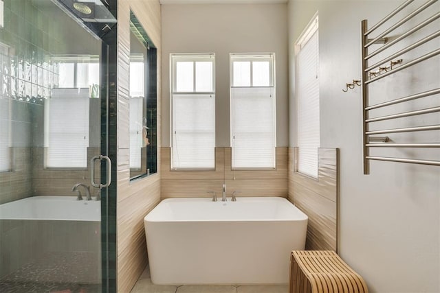 3824 Library Ln, Edmond, OK 73034 - full bath featuring a towel warmer, healthy amount of natural light, a freestanding bath, and tile walls