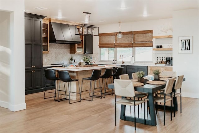 118900 S 4213th Rd, Eufaula, OK 74432 - kitchen with premium range hood, decorative backsplash, a breakfast bar, a kitchen island, and light countertops