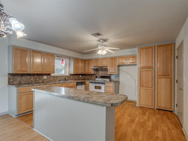 2822 N Market Ave, Shawnee, OK 74804 - kitchen with white gas stove, under cabinet range hood, decorative backsplash, light wood finished floors, and ceiling fan