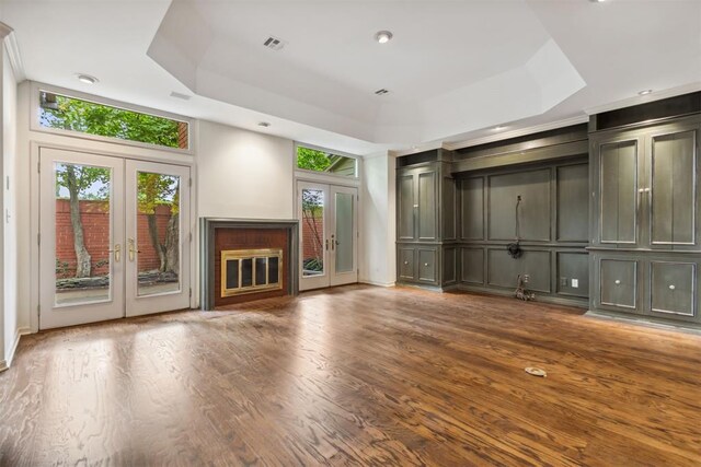 2825 NW Grand Blvd Unit 3, Oklahoma City, OK 73116 - unfurnished living room featuring french doors, a raised ceiling, a decorative wall, and wood finished floors