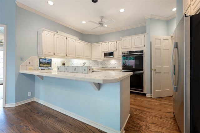2825 NW Grand Blvd Unit 3, Oklahoma City, OK 73116 - kitchen with stainless steel appliances, a peninsula, tasteful backsplash, a kitchen bar, and recessed lighting