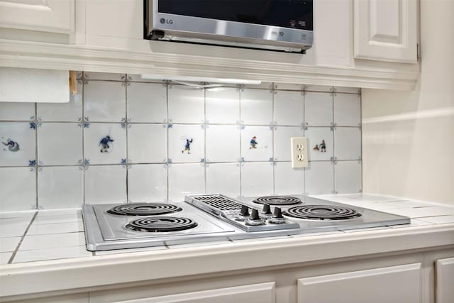 2825 NW Grand Blvd Unit 3, Oklahoma City, OK 73116 - kitchen with stainless steel electric stovetop, white cabinets, and tasteful backsplash