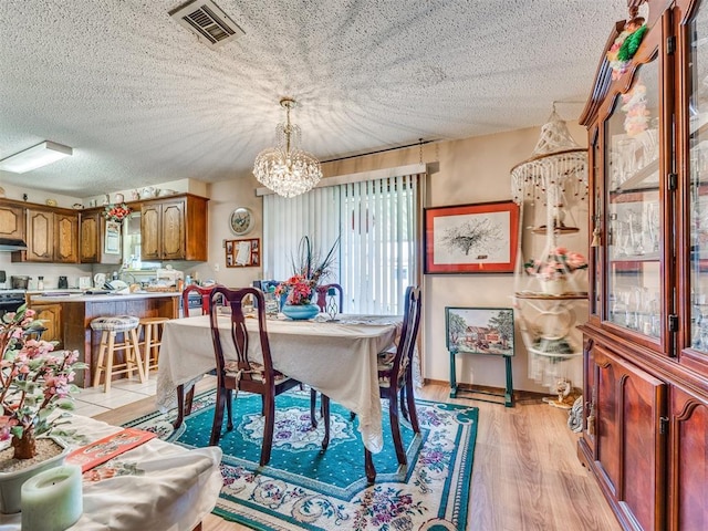 4021 E Larkwood Dr, Del City, OK 73115 - dining area featuring a chandelier, light wood finished floors, and a textured ceiling