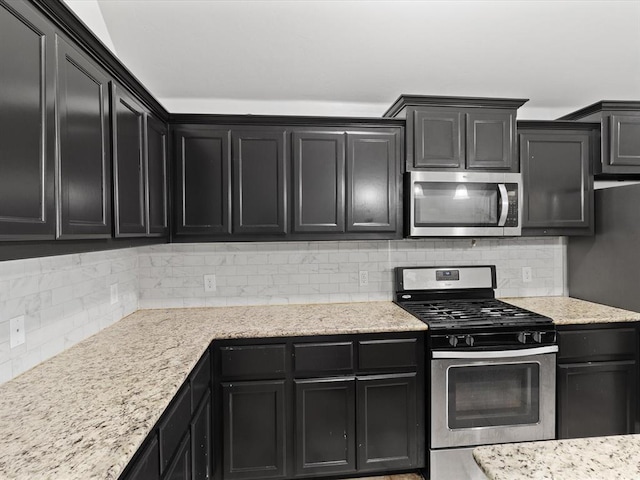 3325 NW 161st St, Edmond, OK 73013 - kitchen with stainless steel appliances, tasteful backsplash, dark cabinets, and light stone countertops