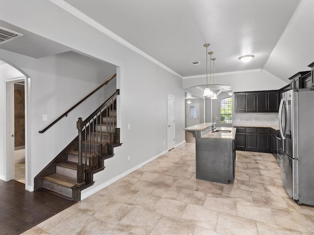 3325 NW 161st St, Edmond, OK 73013 - kitchen with freestanding refrigerator, arched walkways, decorative light fixtures, an island with sink, and crown molding