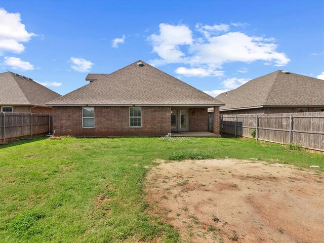 3325 NW 161st St, Edmond, OK 73013 - rear view of house with brick siding, a fenced backyard, a patio, and a shingled roof