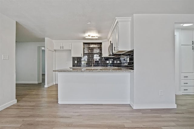 813 SW 56th St, Oklahoma City, OK 73109 - kitchen with white cabinetry, light stone countertops, tasteful backsplash, and light wood-type flooring