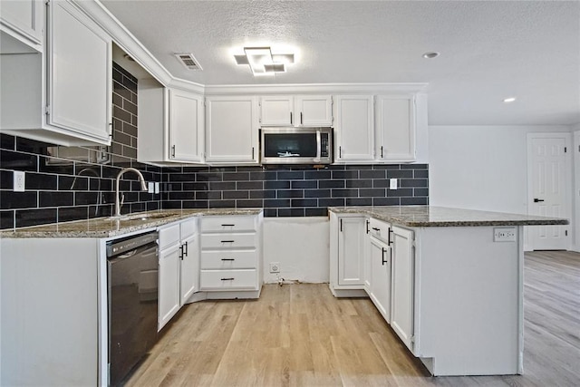813 SW 56th St, Oklahoma City, OK 73109 - kitchen with stainless steel microwave, black dishwasher, light stone counters, light wood-type flooring, and recessed lighting