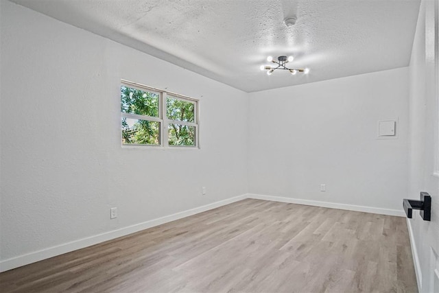 813 SW 56th St, Oklahoma City, OK 73109 - spare room featuring light wood finished floors, a textured ceiling, and a chandelier