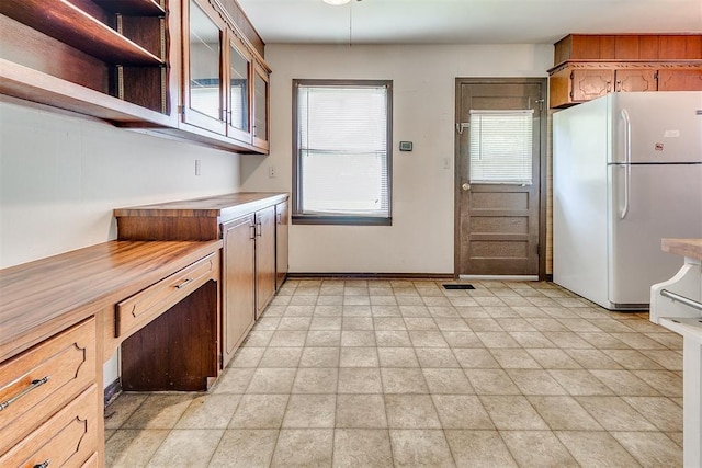 1817 W Harrison Ave, Guthrie, OK 73044 - kitchen with freestanding refrigerator, glass insert cabinets, light countertops, and open shelves