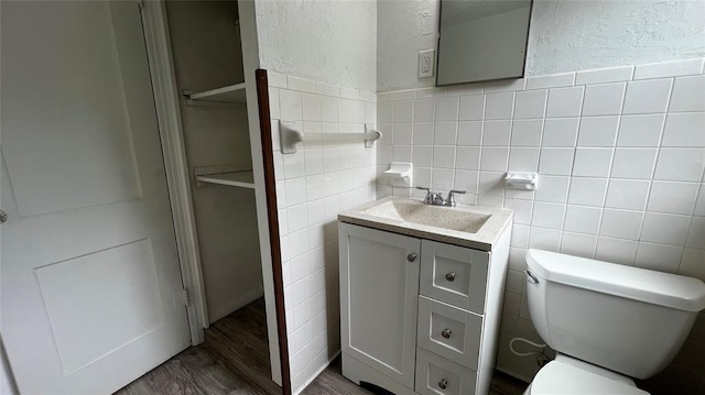 425 Mohawk Dr, Pauls Valley, OK 73075 - half bathroom featuring vanity, a textured wall, tile walls, and wood finished floors