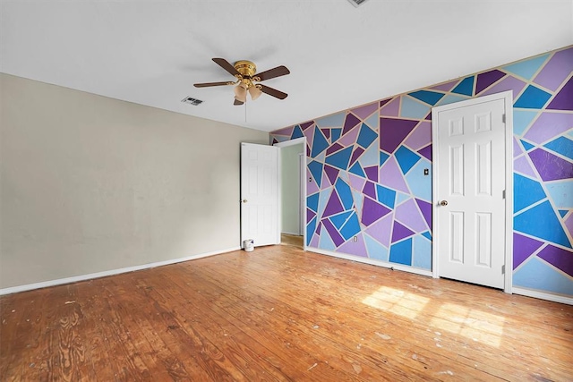 231 W Polk St, Mangum, OK 73554 - unfurnished bedroom with hardwood / wood-style flooring, an accent wall, wallpapered walls, and ceiling fan