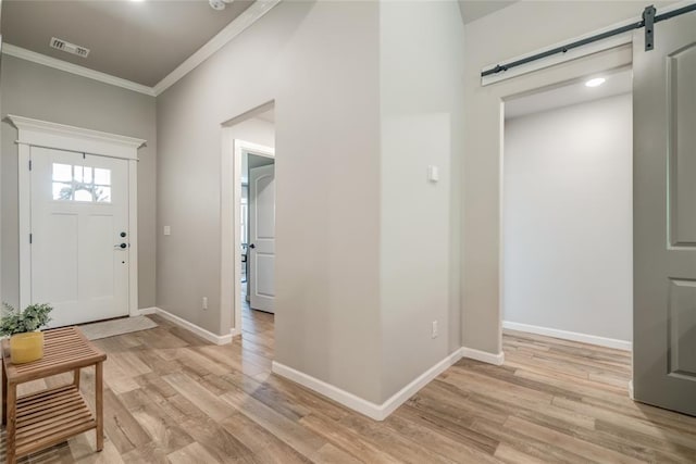 13420 Saltgrass Dr, Edmond, OK 73025 - entrance foyer featuring a barn door, crown molding, and light wood finished floors