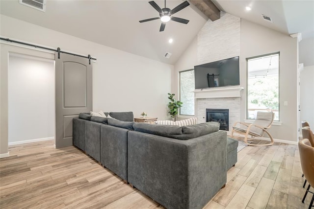 13420 Saltgrass Dr, Edmond, OK 73025 - living room with a ceiling fan, beamed ceiling, light wood finished floors, a stone fireplace, and a barn door
