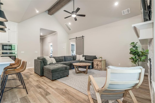 13420 Saltgrass Dr, Edmond, OK 73025 - living room featuring beam ceiling, ceiling fan, light wood finished floors, a barn door, and high vaulted ceiling