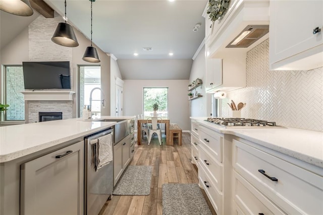13420 Saltgrass Dr, Edmond, OK 73025 - kitchen featuring appliances with stainless steel finishes, vaulted ceiling, light wood-type flooring, tasteful backsplash, and custom exhaust hood