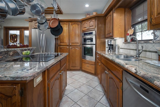 2205 SE 90th St, Lawton, OK 73501 - kitchen with appliances with stainless steel finishes, brown cabinets, decorative backsplash, light tile patterned flooring, and dark stone counters