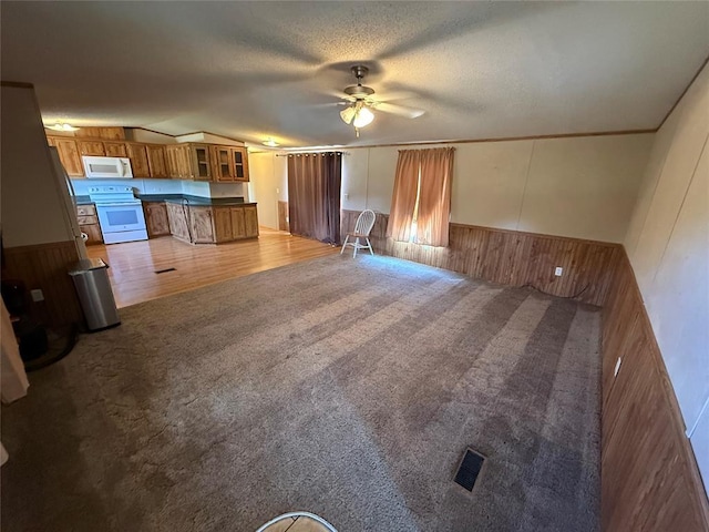 339133 E 870th Rd, Chandler, OK 74834 - unfurnished living room with wood walls, carpet flooring, a ceiling fan, wainscoting, and vaulted ceiling