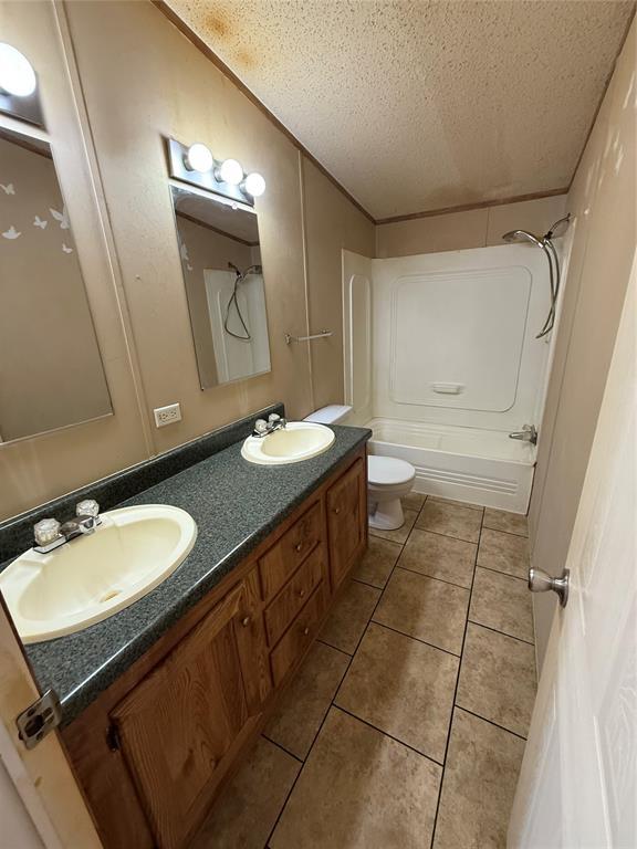 339133 E 870th Rd, Chandler, OK 74834 - full bath with a textured ceiling, double vanity, shower / bath combination, and tile patterned floors