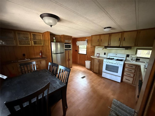 120347 S 4186th Rd, Eufaula, OK 74432 - kitchen with stainless steel appliances, under cabinet range hood, brown cabinets, wood walls, and a textured ceiling