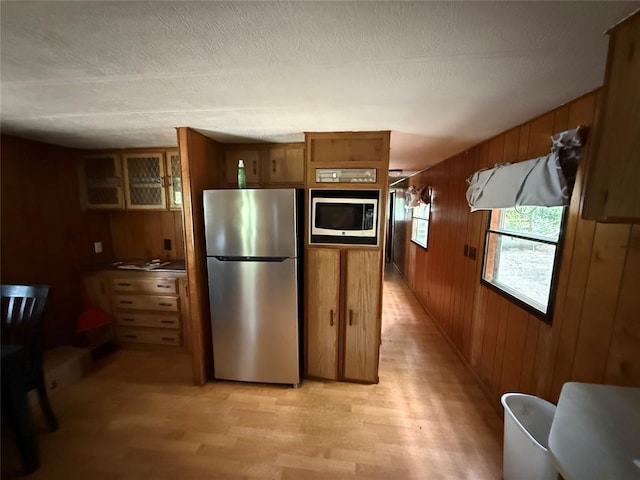 120347 S 4186th Rd, Eufaula, OK 74432 - kitchen with appliances with stainless steel finishes, wood walls, light wood-type flooring, brown cabinets, and glass insert cabinets