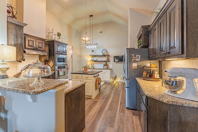 2432 NW 175th St, Edmond, OK 73012 - kitchen featuring stainless steel appliances, wood finished floors, light stone countertops, under cabinet range hood, and high vaulted ceiling