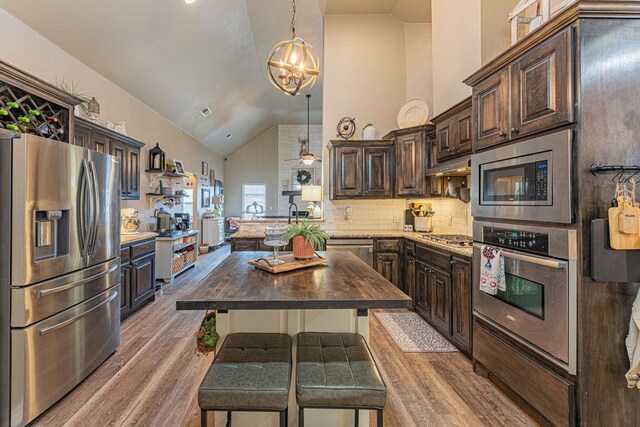 2432 NW 175th St, Edmond, OK 73012 - kitchen with stainless steel appliances, high vaulted ceiling, light wood-style flooring, dark brown cabinets, and butcher block countertops