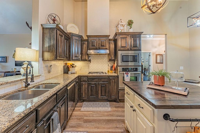 2432 NW 175th St, Edmond, OK 73012 - kitchen featuring stainless steel appliances, light wood-type flooring, dark brown cabinetry, and dark stone countertops