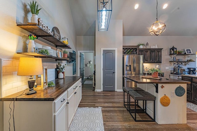 2432 NW 175th St, Edmond, OK 73012 - kitchen with stainless steel fridge with ice dispenser, open shelves, butcher block counters, tasteful backsplash, and high vaulted ceiling