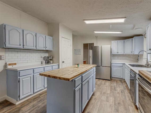 7401 E Forrest Hills Rd, Guthrie, OK 73044 - kitchen featuring appliances with stainless steel finishes, wood counters, gray cabinets, light wood-style flooring, and tasteful backsplash