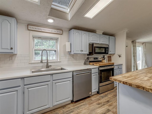 7401 E Forrest Hills Rd, Guthrie, OK 73044 - kitchen with appliances with stainless steel finishes, a skylight, light wood-style flooring, backsplash, and recessed lighting