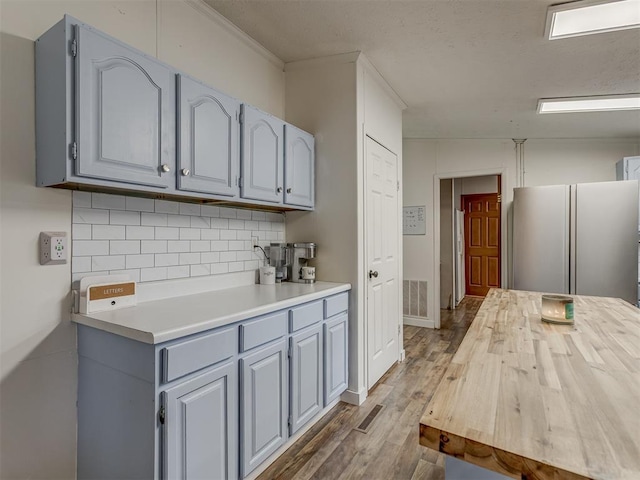7401 E Forrest Hills Rd, Guthrie, OK 73044 - kitchen featuring freestanding refrigerator, gray cabinets, wood finished floors, tasteful backsplash, and light countertops
