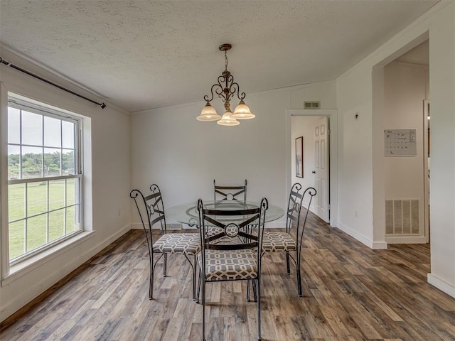 7401 E Forrest Hills Rd, Guthrie, OK 73044 - dining room with wood finished floors, a textured ceiling, and a chandelier