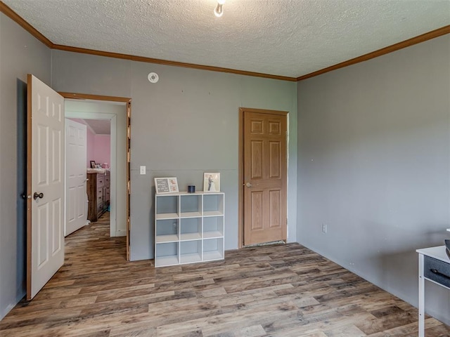 7401 E Forrest Hills Rd, Guthrie, OK 73044 - unfurnished bedroom featuring ornamental molding, wood finished floors, and a textured ceiling