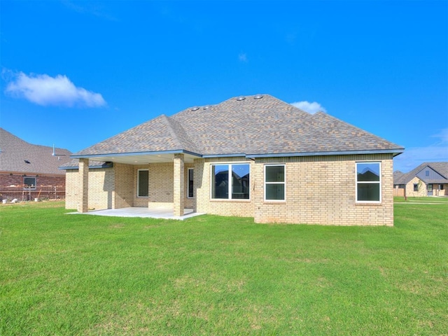 1136 Jozie Way, Tuttle, OK 73089 - back of property featuring brick siding, a patio area, a lawn, and roof with shingles