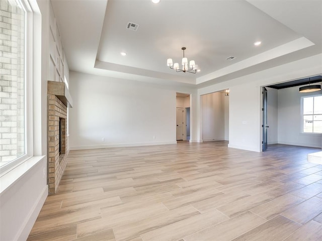1136 Jozie Way, Tuttle, OK 73089 - unfurnished living room featuring a tray ceiling, a chandelier, a fireplace, light wood-type flooring, and recessed lighting