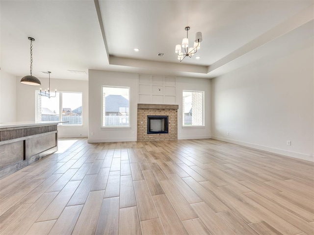1136 Jozie Way, Tuttle, OK 73089 - unfurnished living room featuring a chandelier, light wood finished floors, a tray ceiling, a fireplace, and recessed lighting