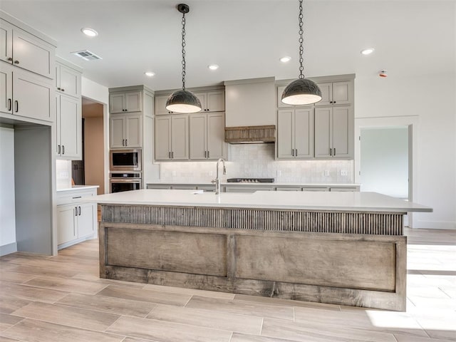 1136 Jozie Way, Tuttle, OK 73089 - kitchen with oven, built in microwave, tasteful backsplash, light countertops, and a center island with sink