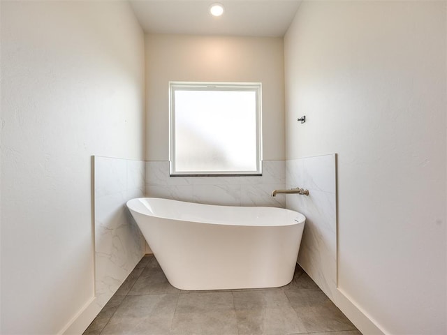 1136 Jozie Way, Tuttle, OK 73089 - bathroom featuring a soaking tub, tile walls, wainscoting, and tile patterned flooring