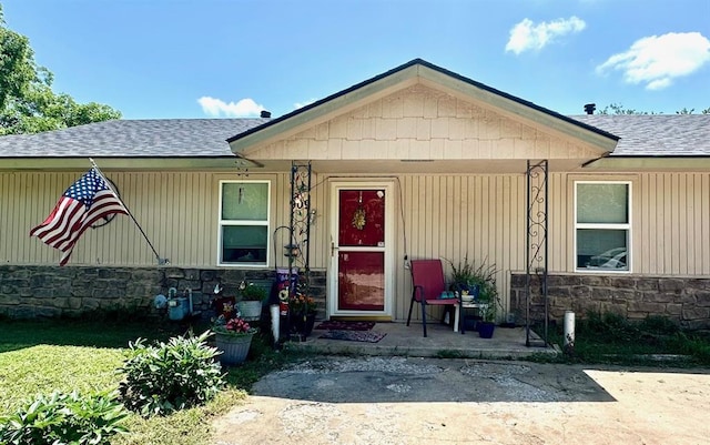 909 N Center St, Shawnee, OK 74801 - view of exterior entry with stone siding, a porch, and a shingled roof