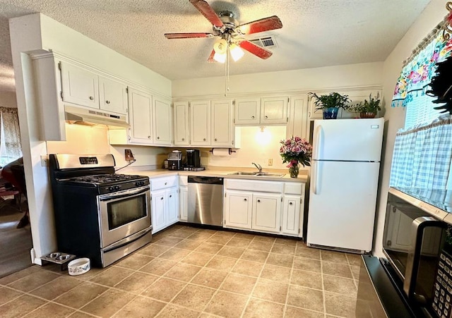 909 N Center St, Shawnee, OK 74801 - kitchen featuring appliances with stainless steel finishes, under cabinet range hood, a ceiling fan, a textured ceiling, and light countertops