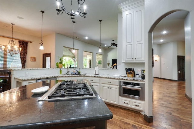 2309 Pinehurst Ct, Shawnee, OK 74801 - kitchen featuring stainless steel appliances, a chandelier, light wood-style floors, arched walkways, and white cabinetry