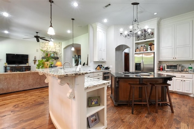 2309 Pinehurst Ct, Shawnee, OK 74801 - kitchen featuring open shelves, appliances with stainless steel finishes, arched walkways, a kitchen breakfast bar, and open floor plan
