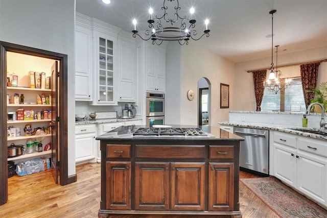 2309 Pinehurst Ct, Shawnee, OK 74801 - kitchen with appliances with stainless steel finishes, a chandelier, arched walkways, light wood-style floors, and white cabinets