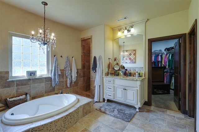 2309 Pinehurst Ct, Shawnee, OK 74801 - bathroom with a chandelier, vanity, a bath, a walk in closet, and stone finish floors