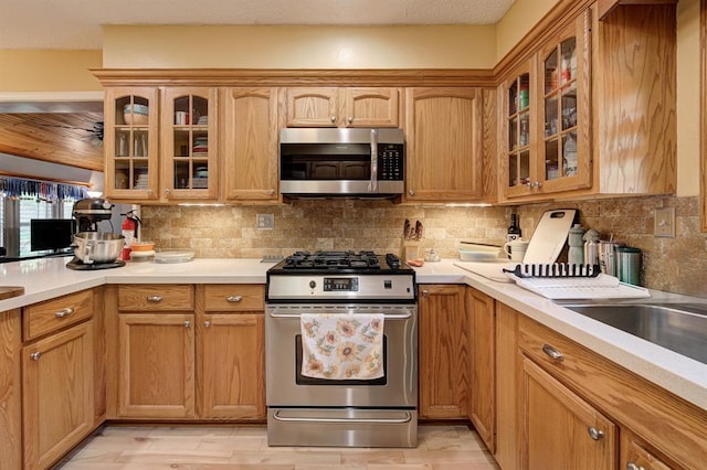 1825 Kings Rd, Edmond, OK 73013 - kitchen featuring stainless steel appliances, light countertops, glass insert cabinets, and decorative backsplash