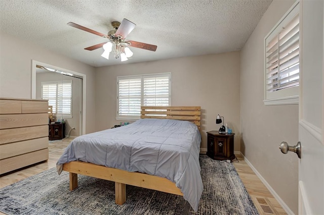 1825 Kings Rd, Edmond, OK 73013 - bedroom featuring light wood finished floors, a textured ceiling, and a ceiling fan