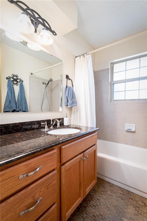 1825 Kings Rd, Edmond, OK 73013 - full bathroom with shower / bath combination with curtain, vanity, and brick patterned flooring