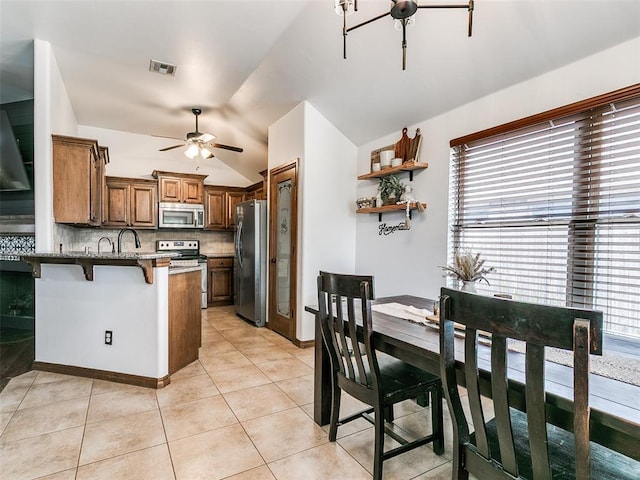 10705 SW 36th St, Yukon, OK 73099 - kitchen with appliances with stainless steel finishes, a ceiling fan, a peninsula, vaulted ceiling, and tasteful backsplash