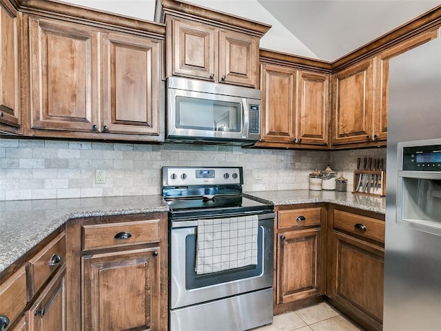 10705 SW 36th St, Yukon, OK 73099 - kitchen featuring stainless steel appliances, backsplash, brown cabinetry, and vaulted ceiling